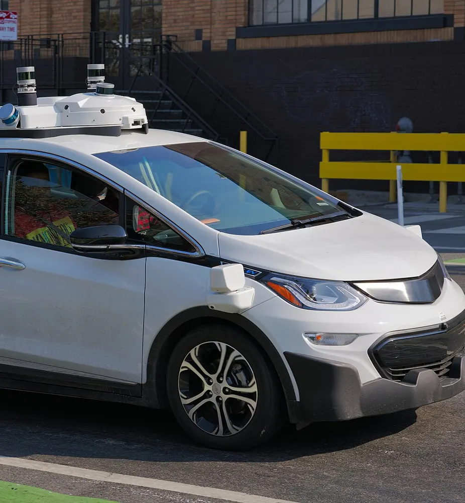 A white Cruise robotaxi with a roof sensor array on a San Francisco street